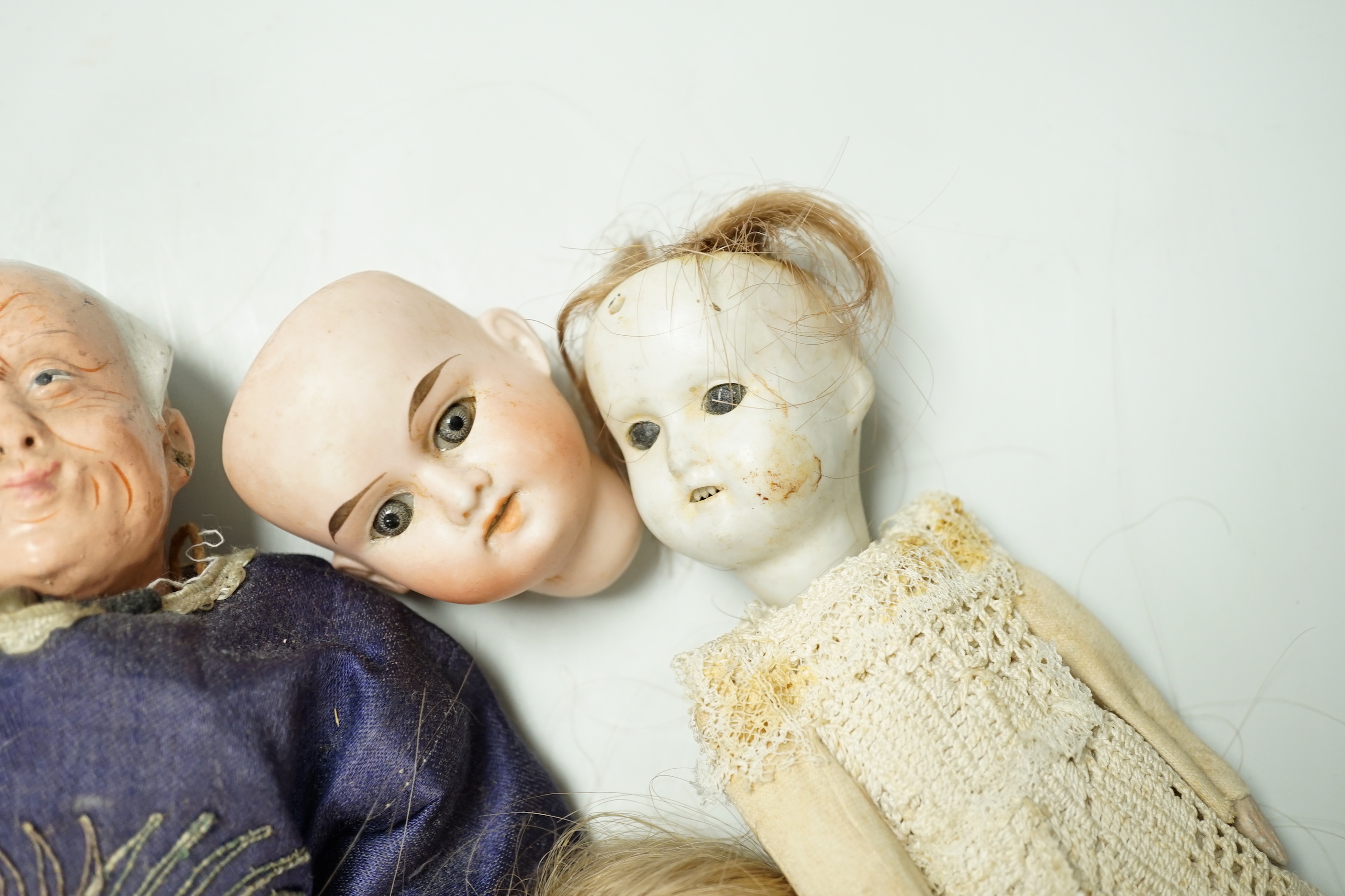 Two Chinese Papier mache dolls with embroidered silk clothing, a pair of Chinese embroidered silk slippers, a similar child’s bonnet a pair of Japanese slippers and three other dolls